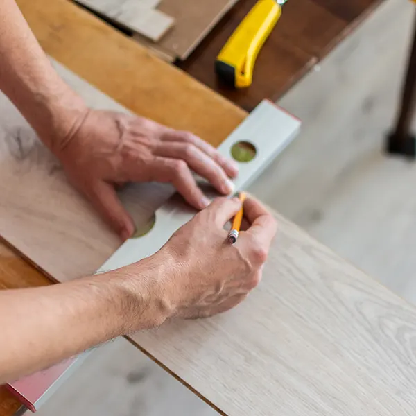 en golvläggare mäter ut vinkeln på ett golvplank.