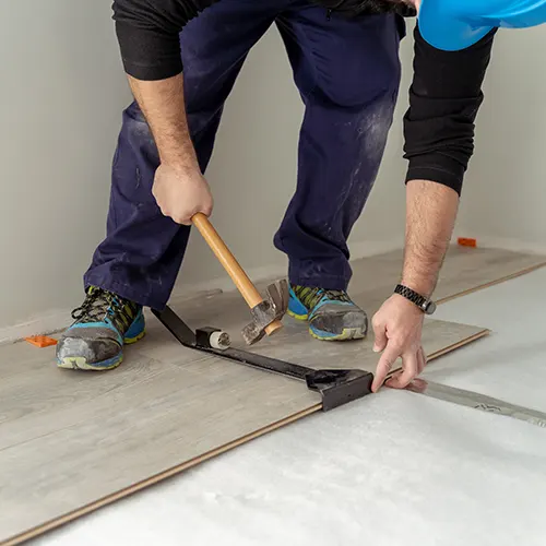 En golvläggare står och monterar ett golv i Hofors